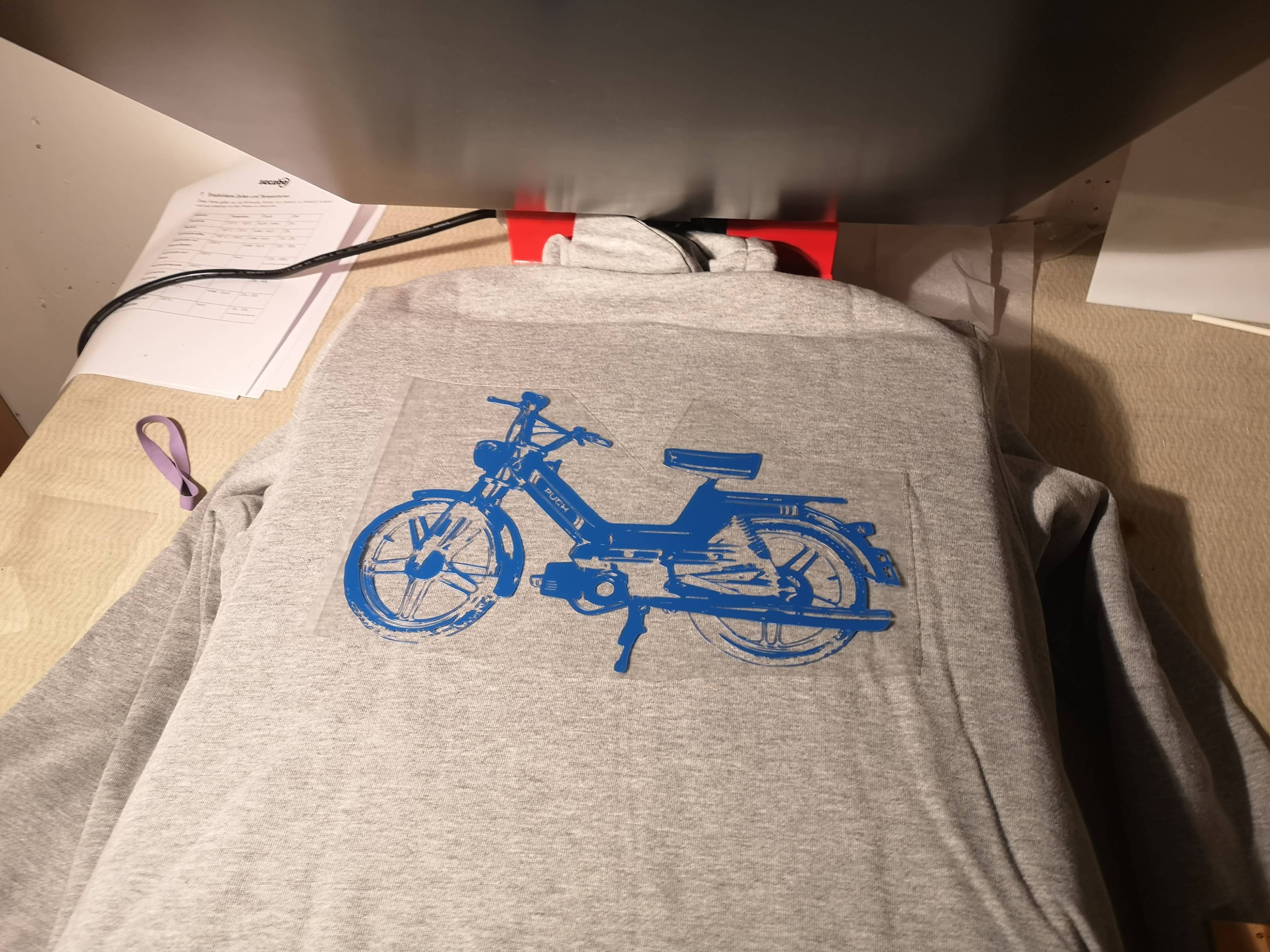 Transferfolie wird auf dem Hoodie positioniert und mit der Presse unter grosser Hitze aufgedruckt